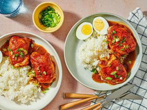 Roast chicken served with rice sauce and garnished with green onions on plates a halved boiled egg included on one plate