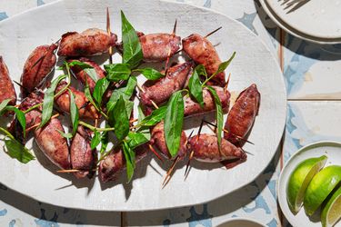 Platter of grilled stuffed squid with garnish displayed on a table with lime wedges and sauce