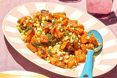 A platter containing grilled sweet potato and corn salad with a serving spoon