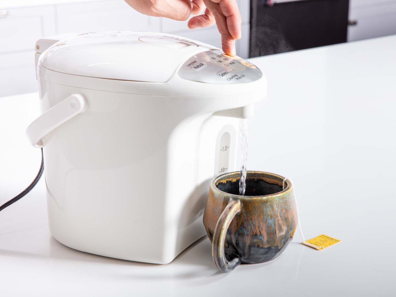 A cup of tea being filled with hot water from the Panasonic water pot