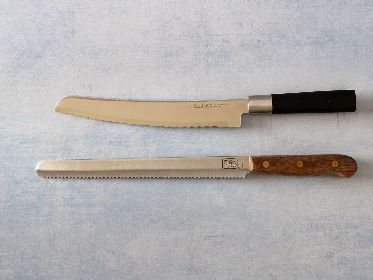 Two bread knives displayed on a light blue countertop