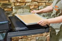 A person places a tray on the Traeger Flatrock Flat Top Grill