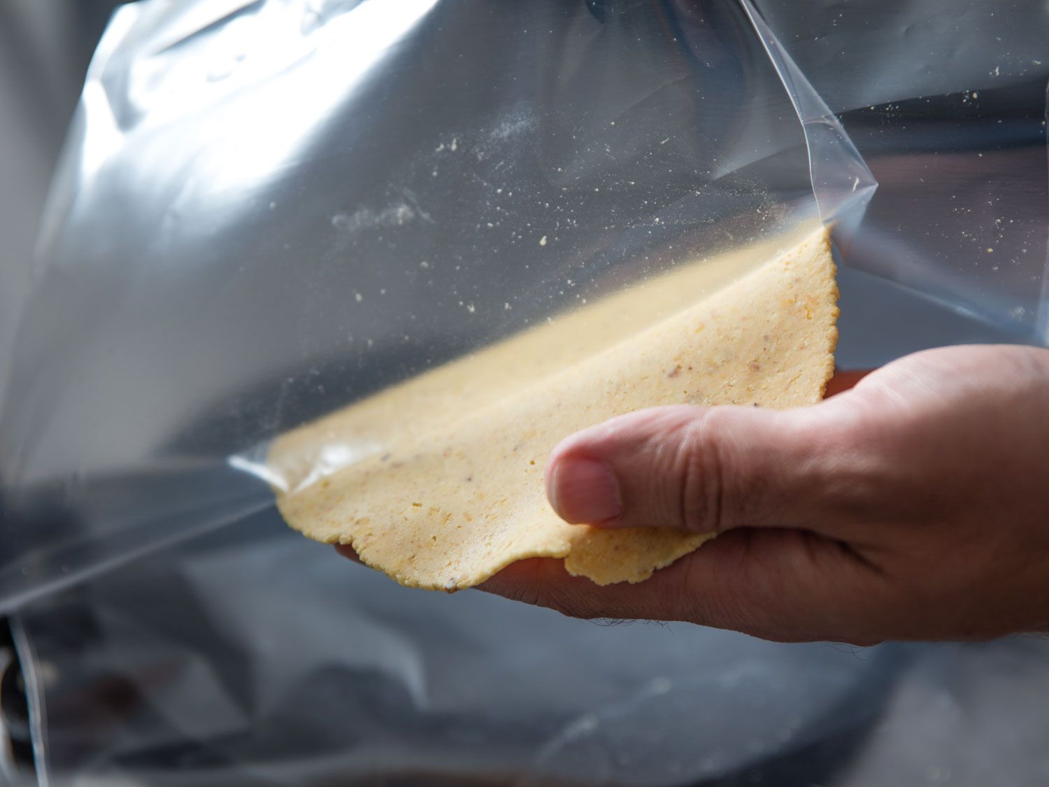 Peeling a freshly-pressed tortilla off plastic
