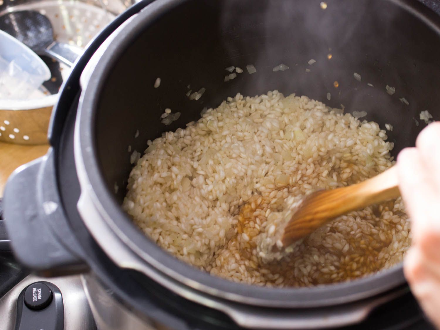 Tossing rice in broth in a pressure cooker. 