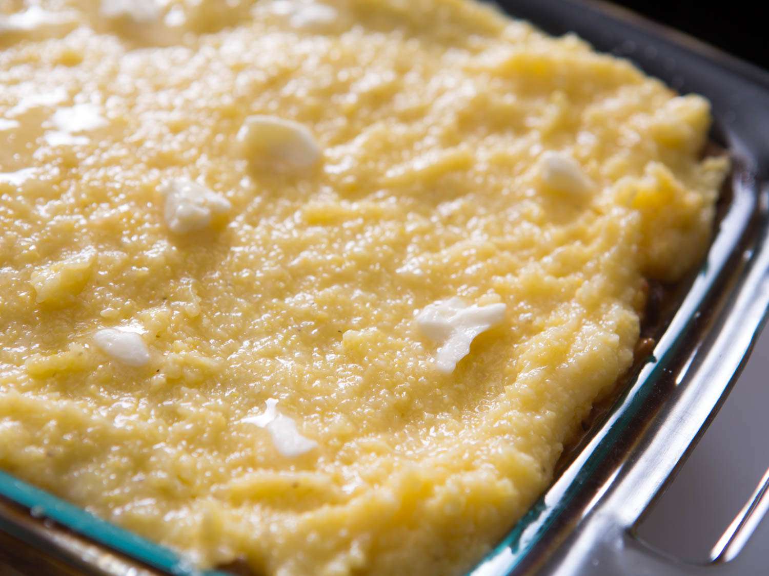 Semi-melted chunks of butter are spaced out atop the final polenta layer.