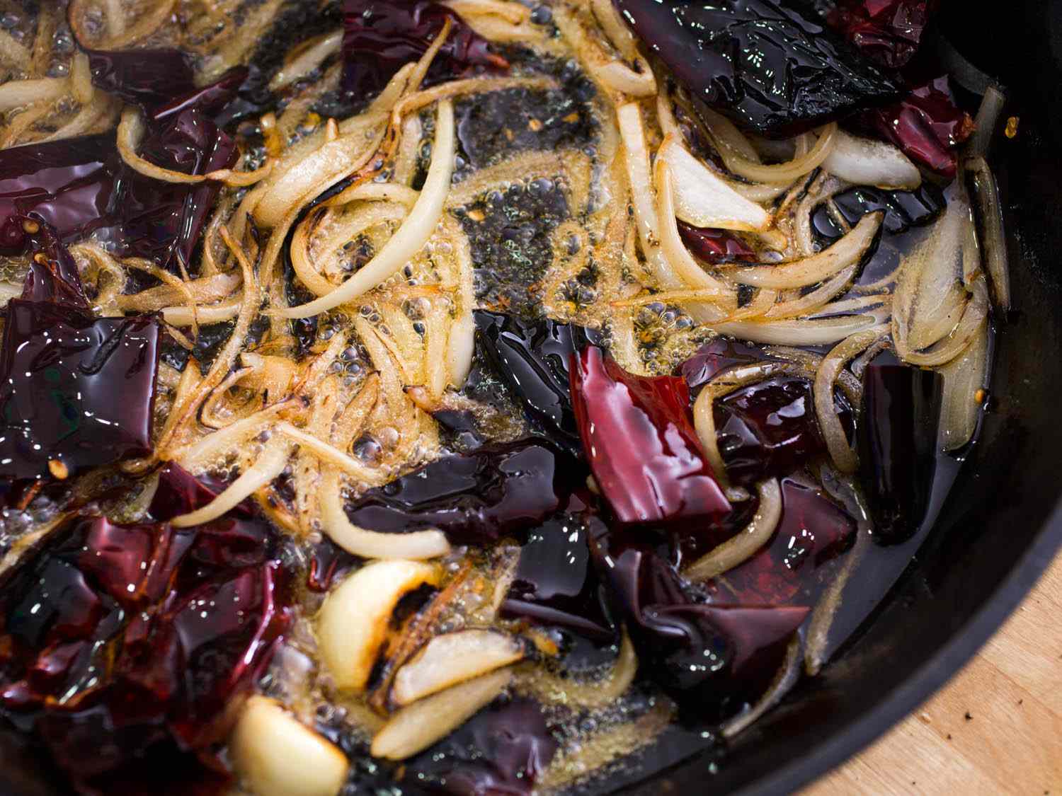 Seared garlic, onion, and charred dried chiles in skillet