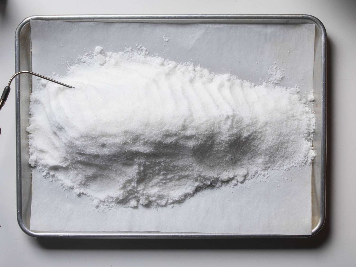 After being fully covered in salt, the fish is no longer visible. The salt looks evenly packed around the fish.