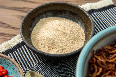 A small bowl of khao khua, or Thai toasted-rice powder, set on a table.