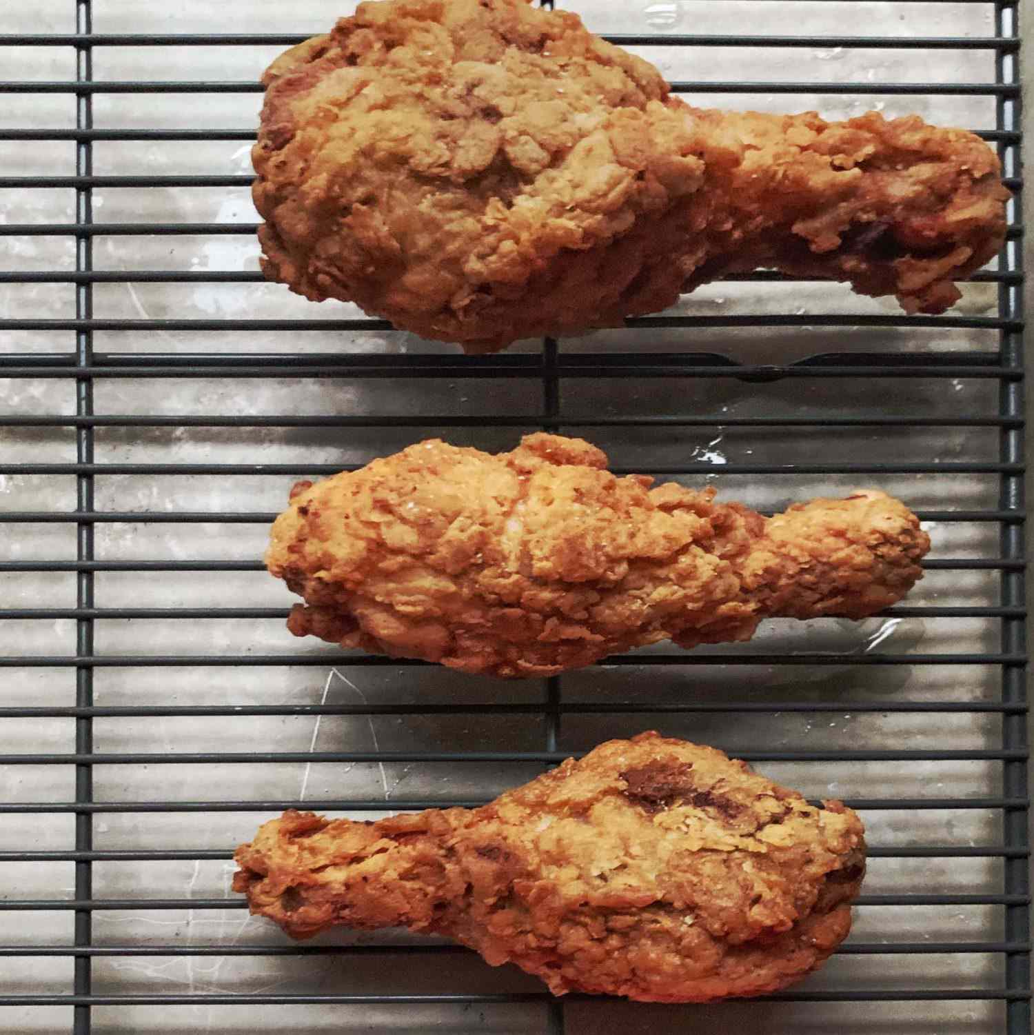 Fried chicken drumsticks cooling on a wire rack