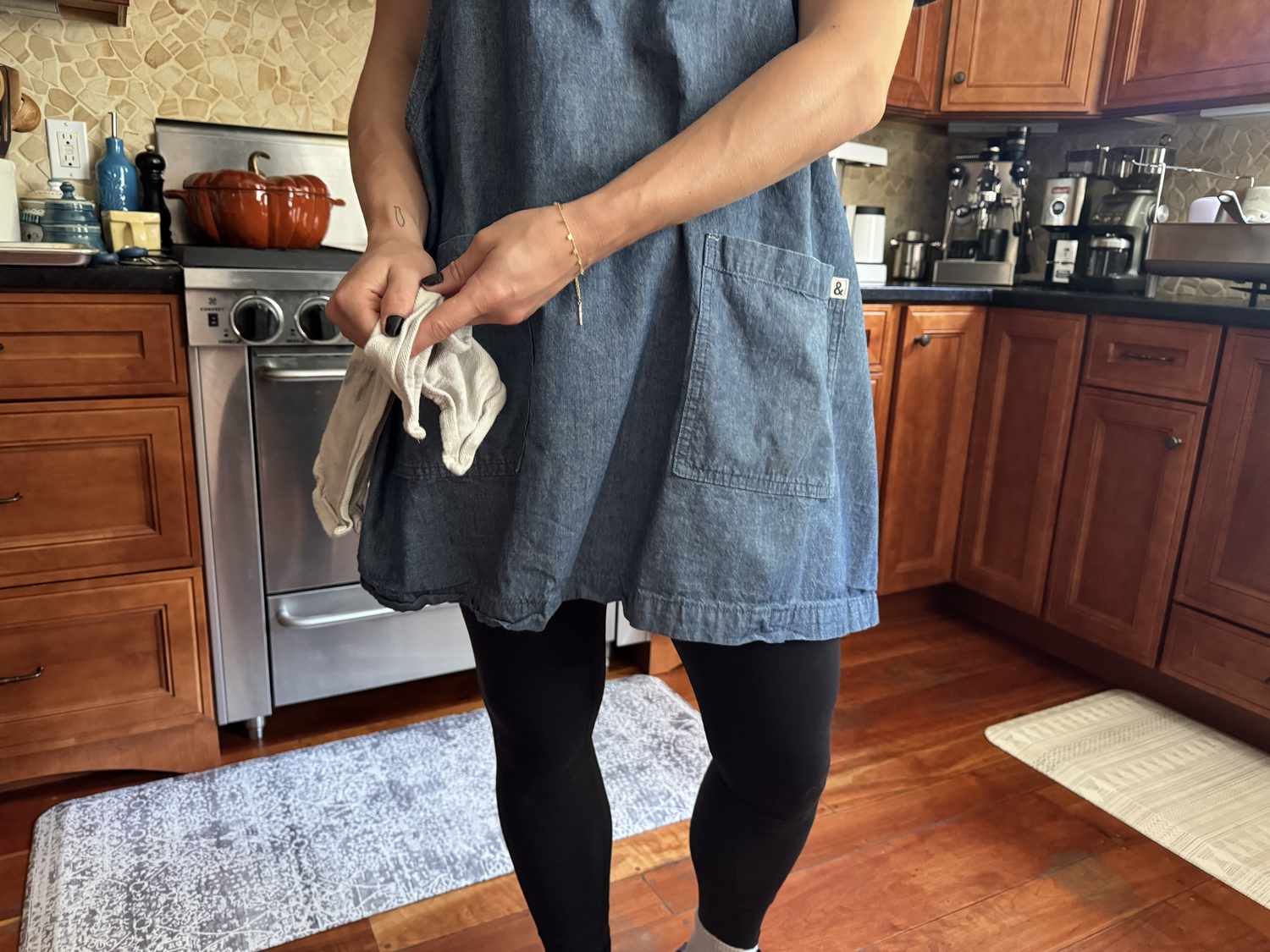 A person drying their handles on a kitchen towel attached to the towel loop on a smock arpon.