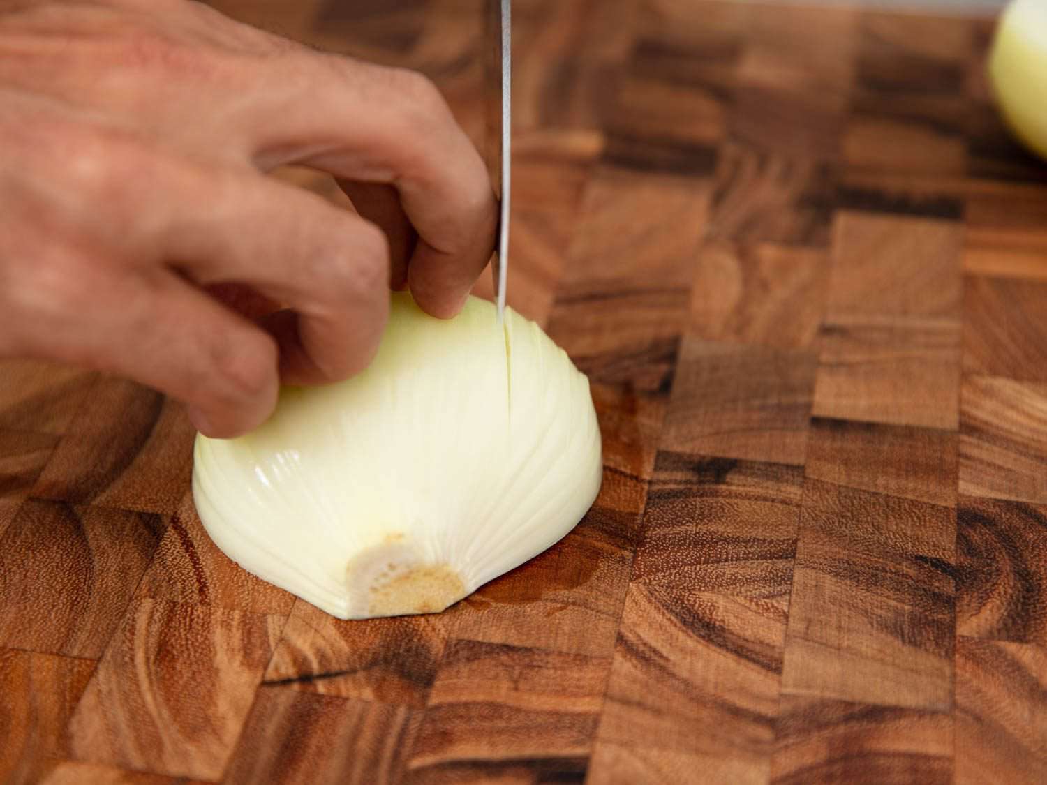 Dicing an onion on a wooden cutting board.