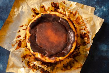 Overhead of a Basque cheesecake resting on two pieces of parchment paper