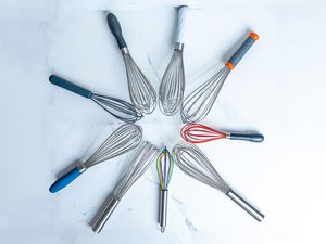 Nine whisks arranged in a circle on a white marble countertop