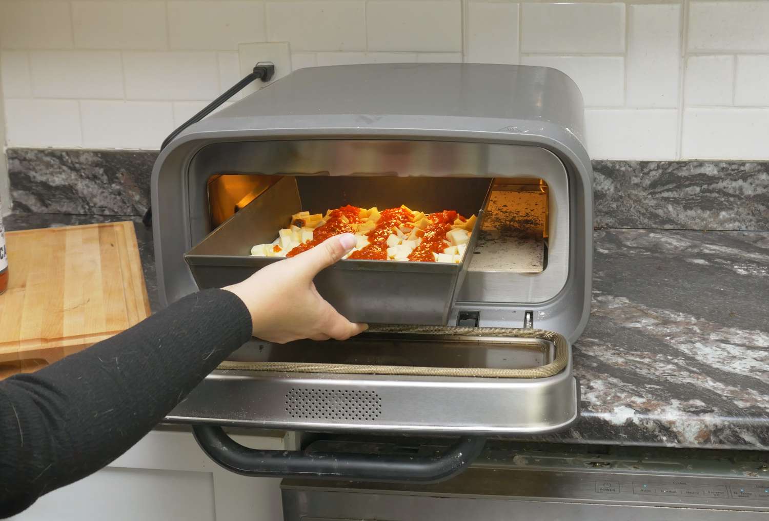 a person putting a pan pizza into a pizza oven