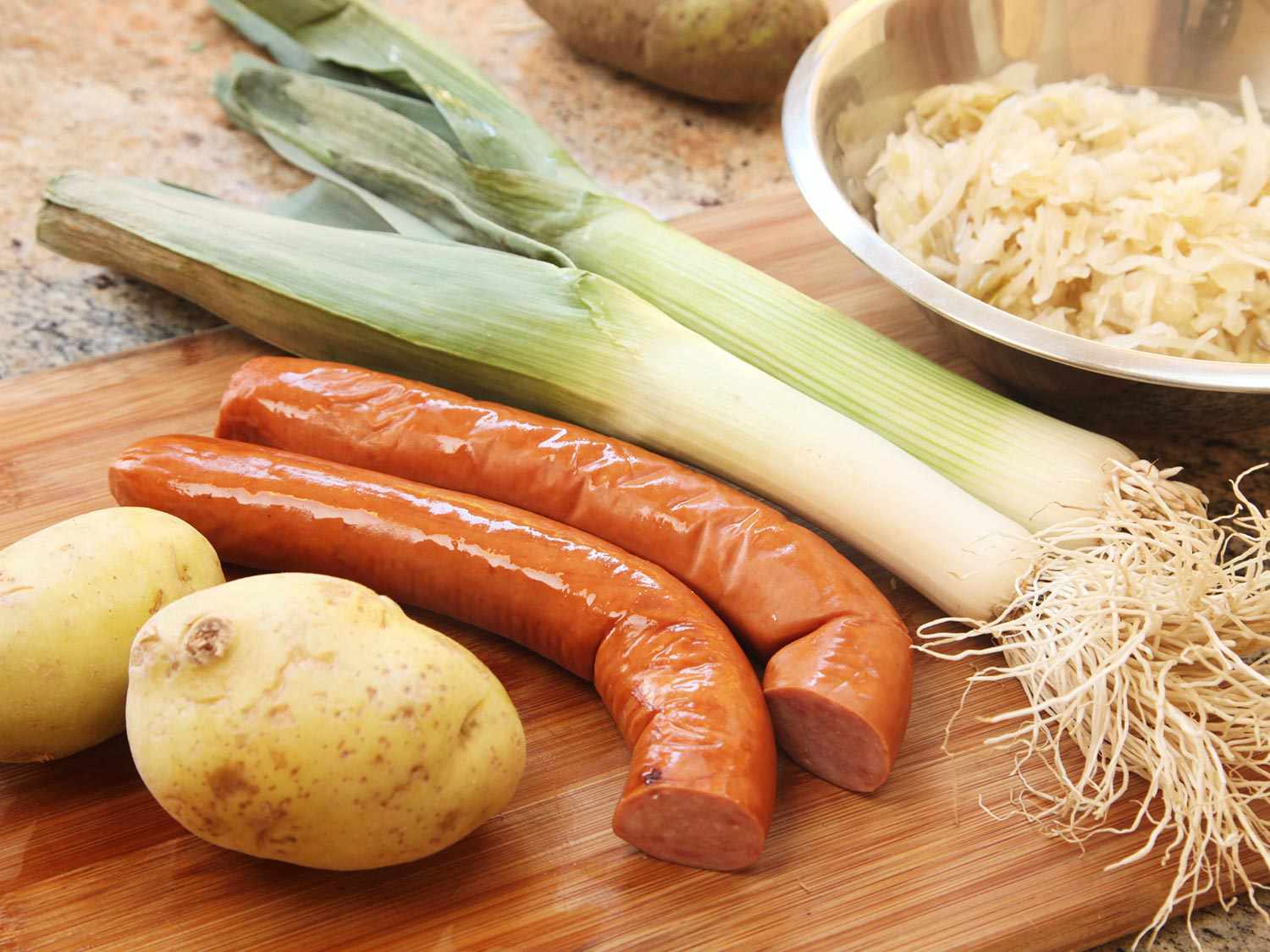 Potatoes, kielbasa, and leeks on a cutting board, ready for making kapusniak soup 