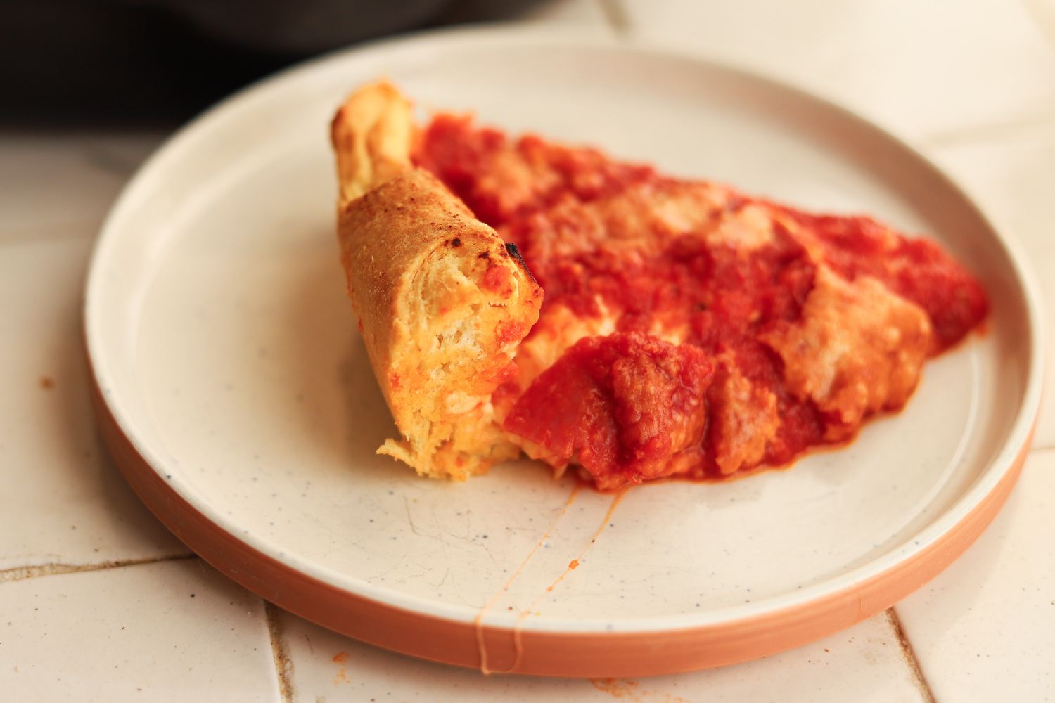 A slice of pizza placed on a plate after using the Emile Henry Deep Dish Pizza Pan