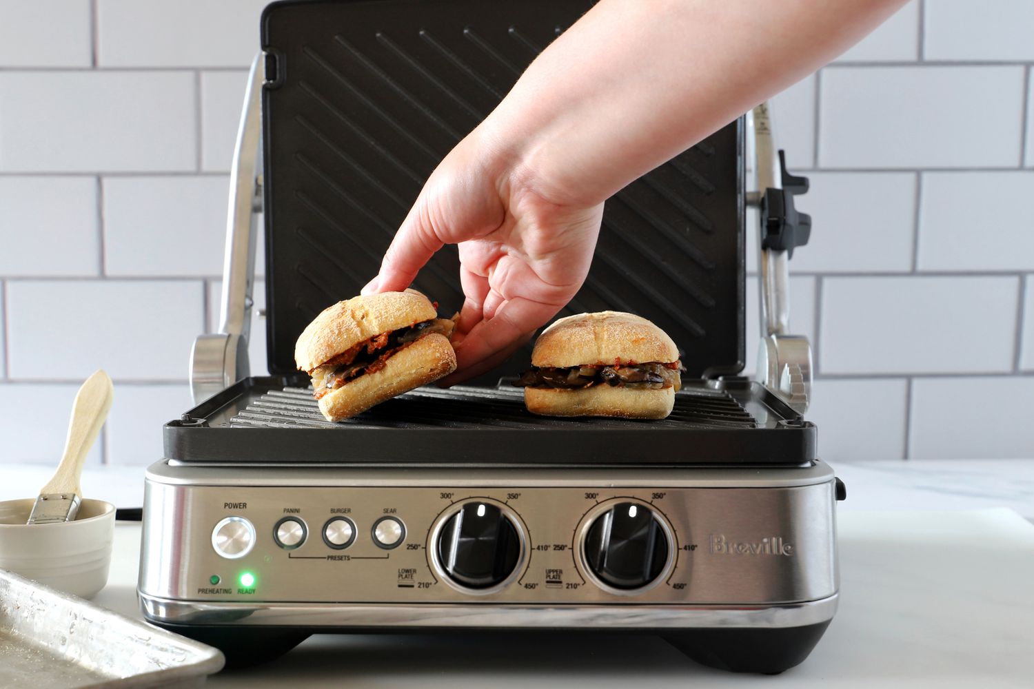 A person adding a sandwich to the Breville panini press.