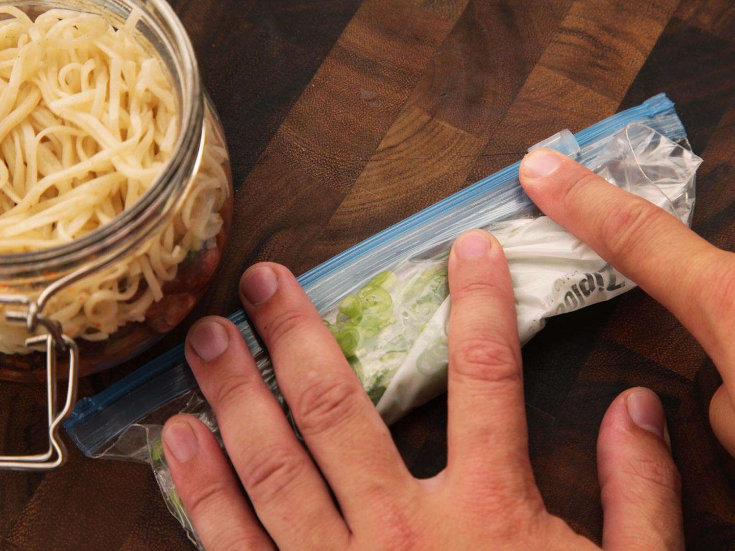 The zip-top bag of scallions and herbs is sealed and rolled up.