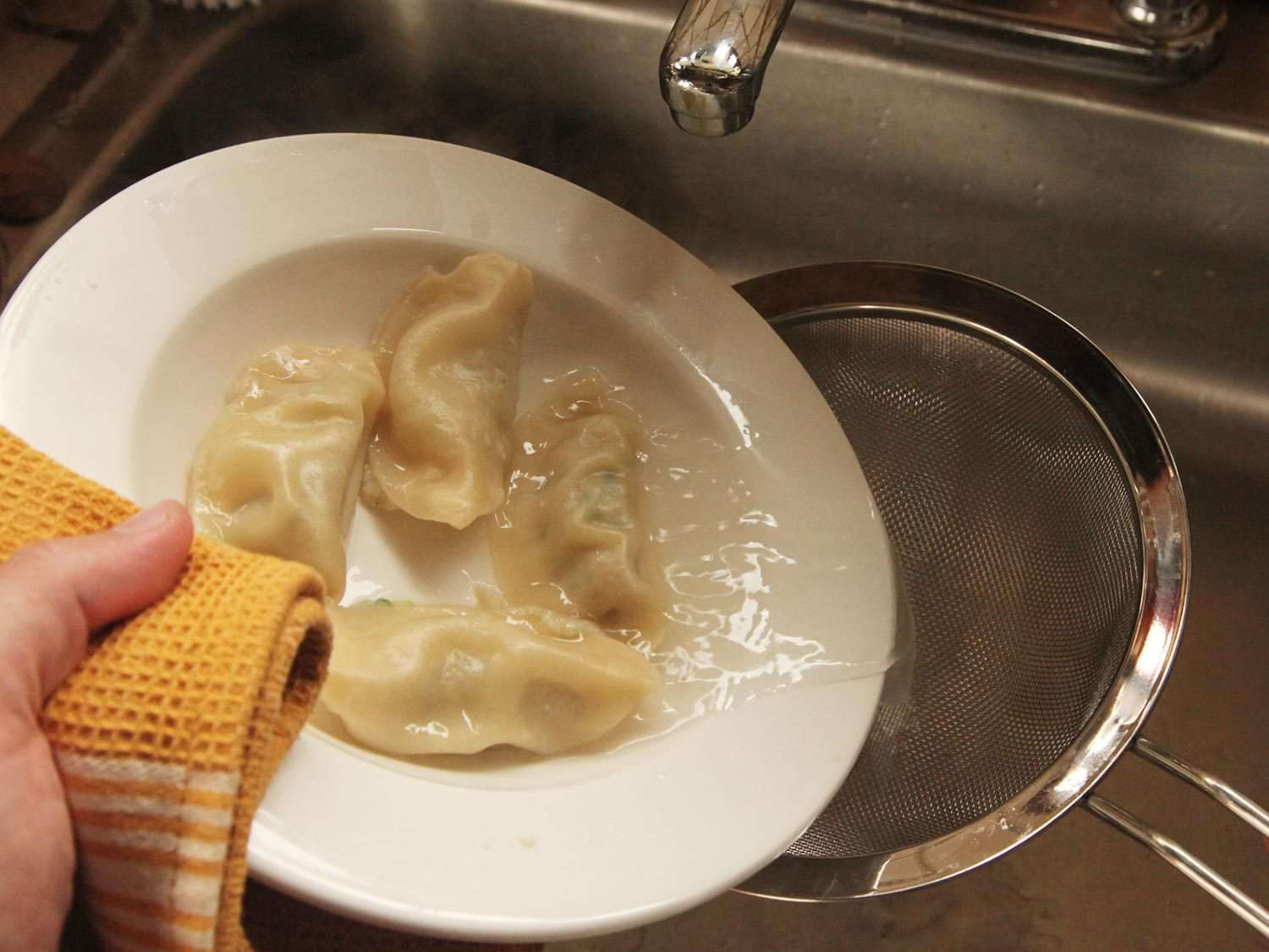 Draining water from a bowl of dumplings.
