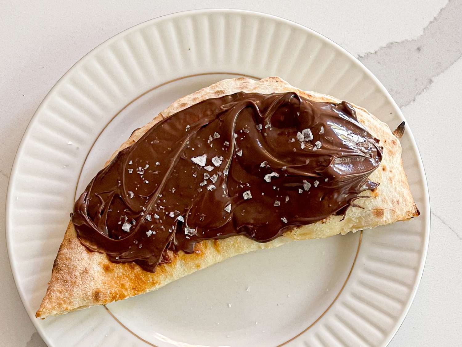 A piece of focaccia spread with Nutella and sprinkled with sea salt