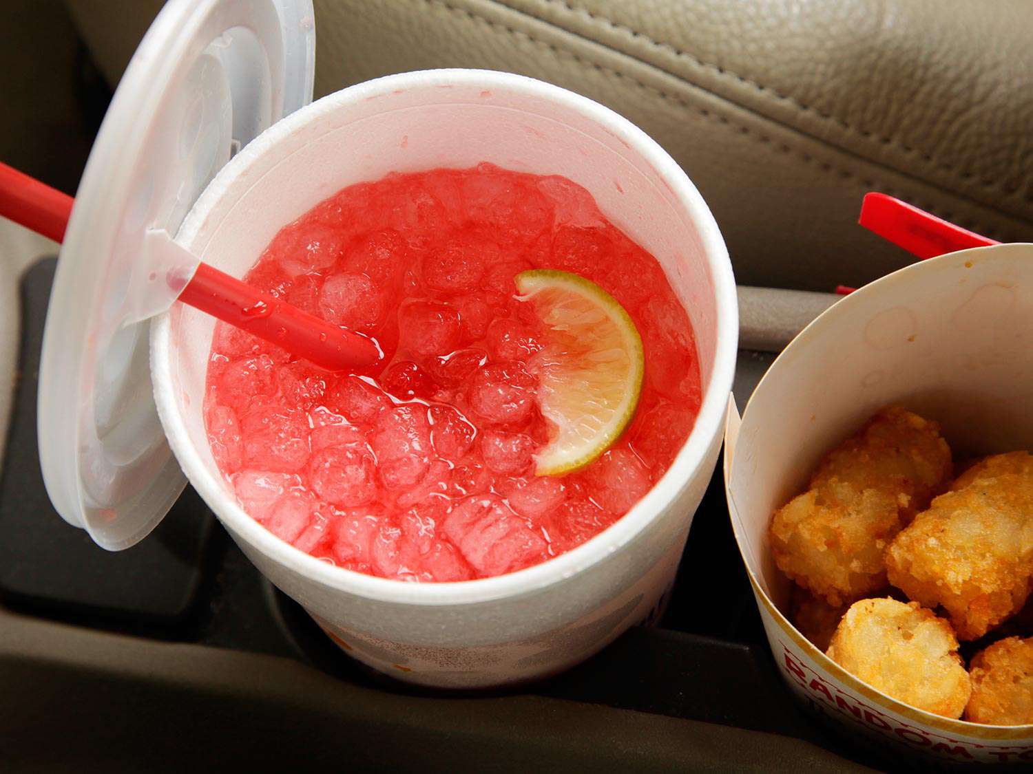 A cherry limeade from Sonic with a container of tater tots on the side 