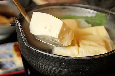 Yudofu (hot water tofu) being spooned out of a bowl.