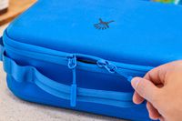 A zipper being pulled open on a blue lunch box.