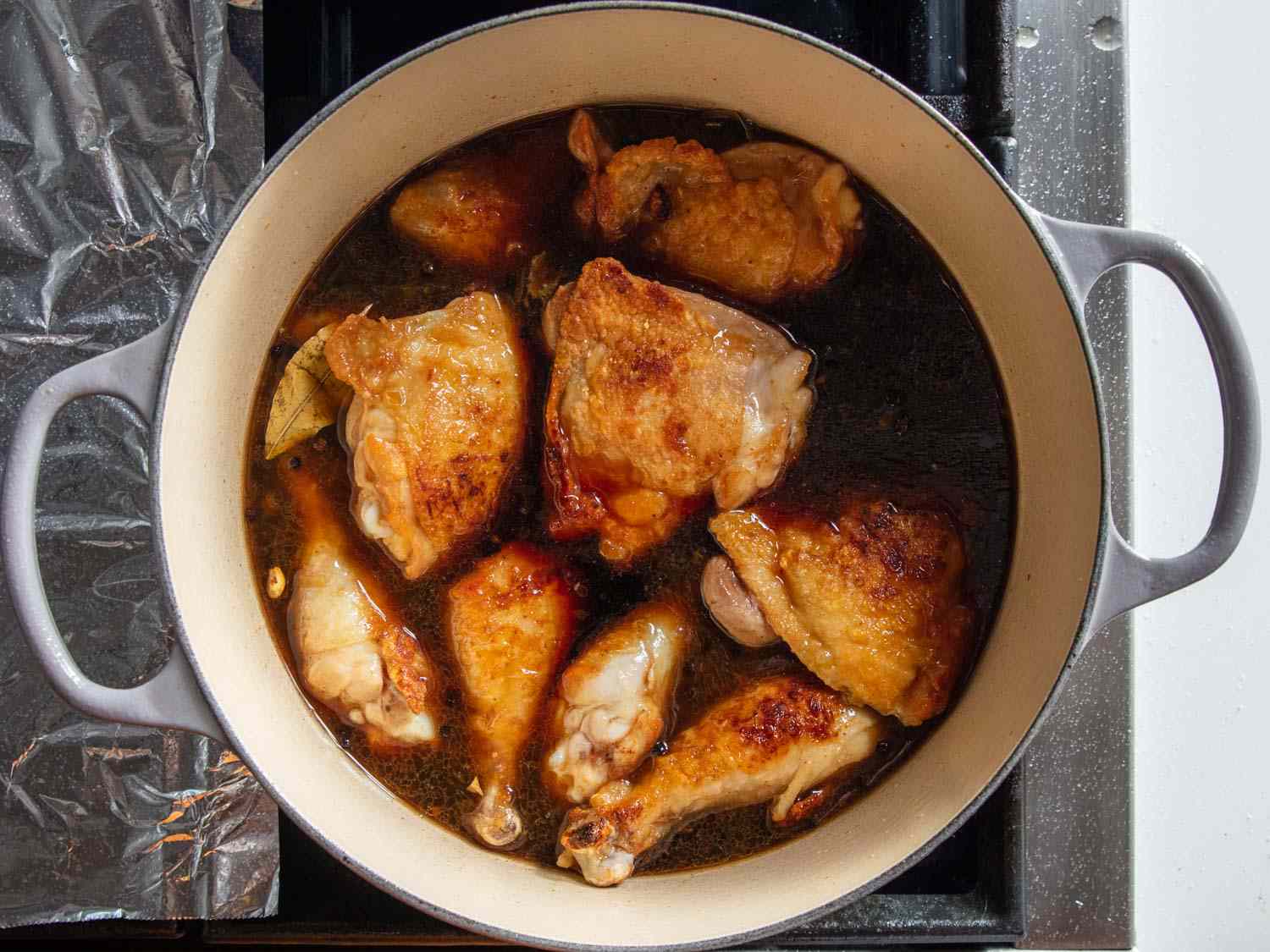Chicken in a vinegary braising sauce for chicken adobo.