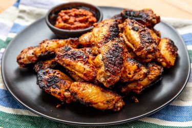 Grilled Turkish chicken wings on a plate with a dipping sauce. 