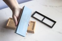 A person showing the fine grit side of a whetstone