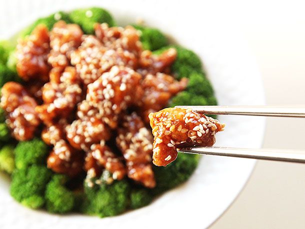 Using chopsticks to pick up a bite of sesame chicken.