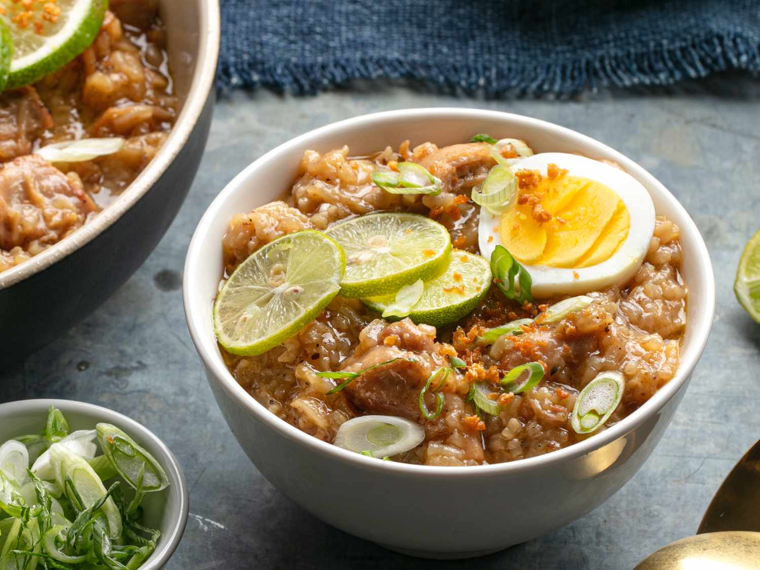 A small bowl of arroz caldo topped with sliced limes and boiled egg.