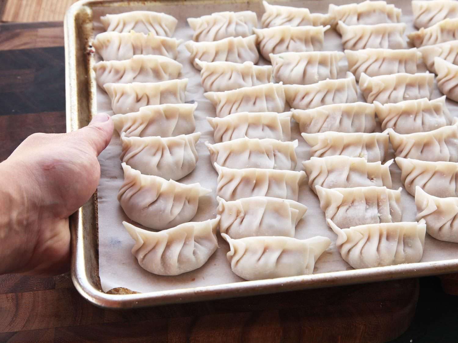 Sheet tray of fresh, uncooked dumplings.