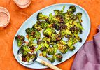 Air-fried broccoli with chili crisp on a blue platter against an orange background.