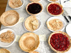 Various pie crusts and fruitfilled pies arranged on a table