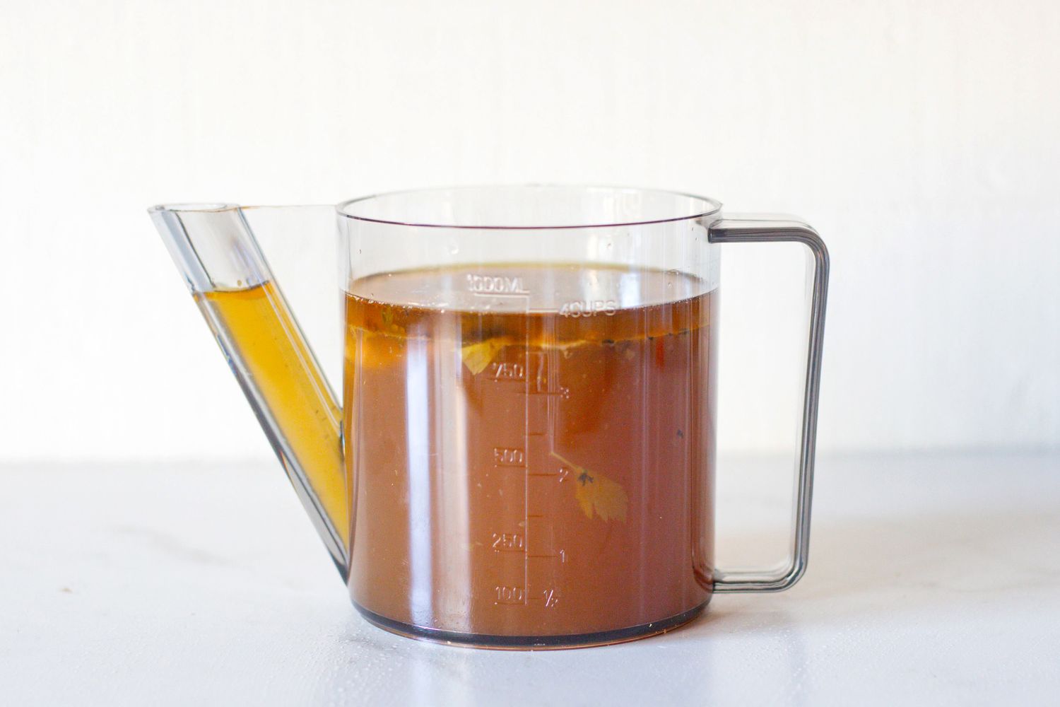 A glass measuring cup with liquid and separate fat layer