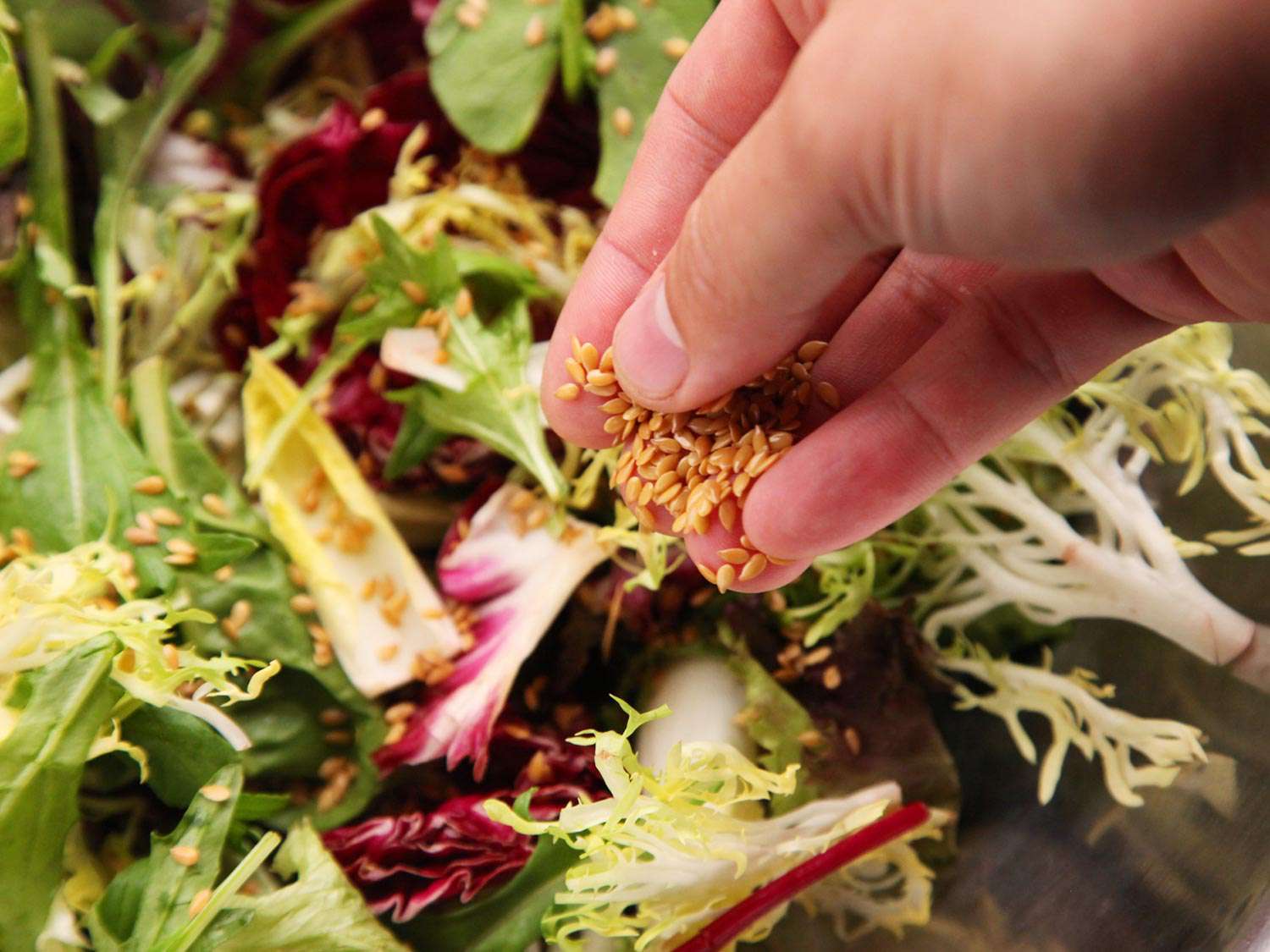 The author sprinkles toasted flax seeds into the salad bowl.