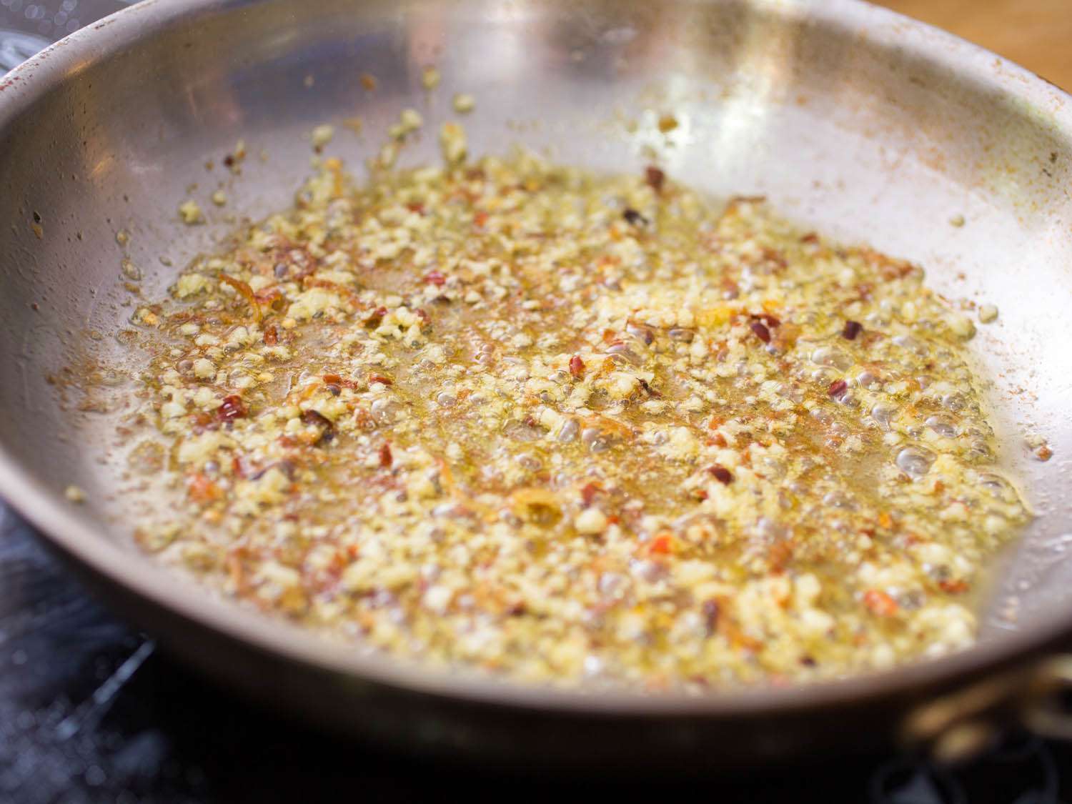 Red pepper flakes and minced garlic browning in olive oil.