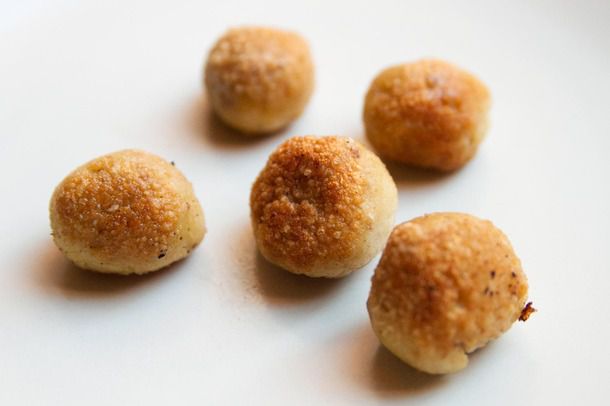 Five lightly golden pan-fried matzo balls arranged on a white background