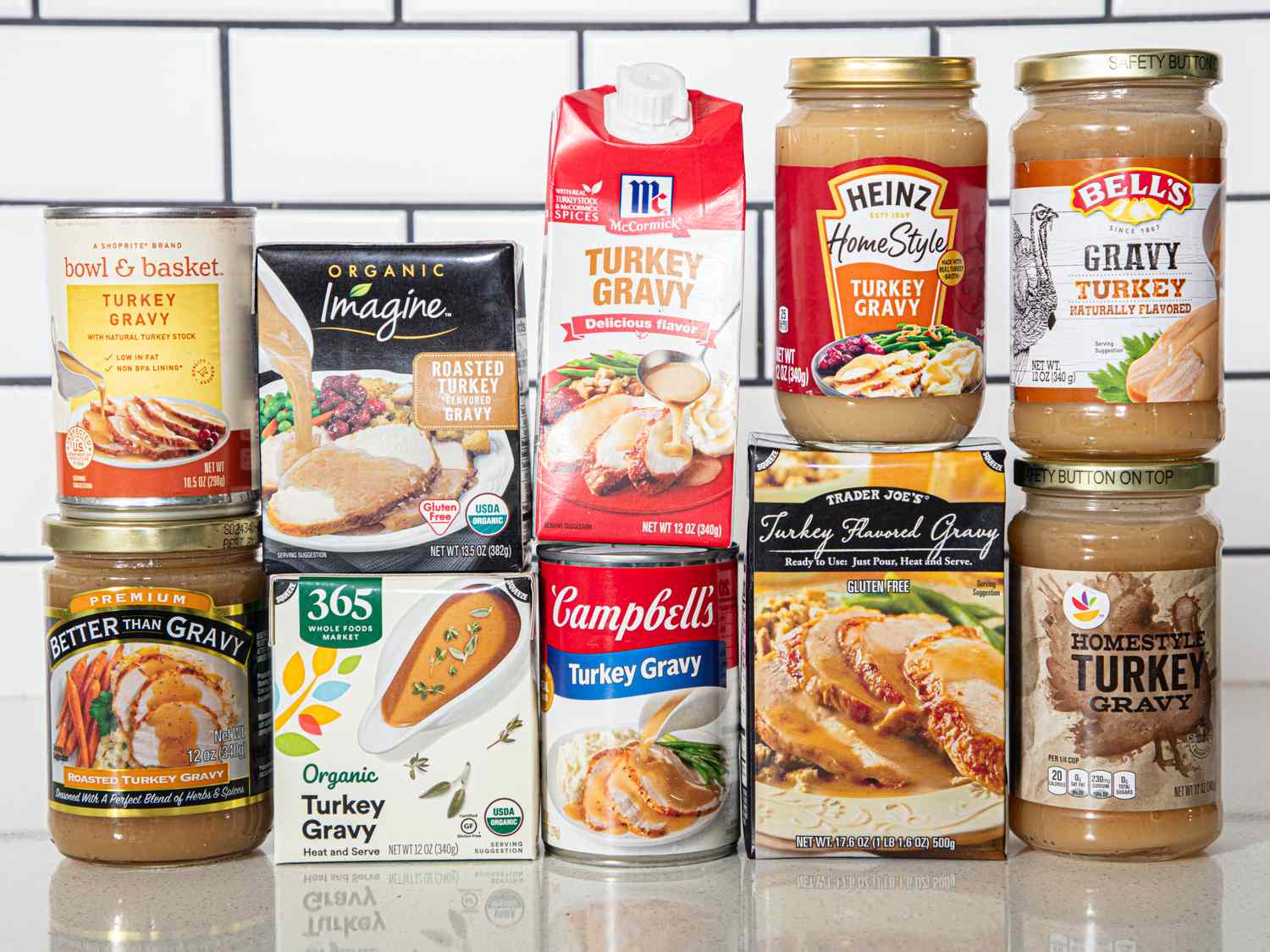 Assorted turkey gravy products displayed on a white tiled background including cartons jars cans and boxes