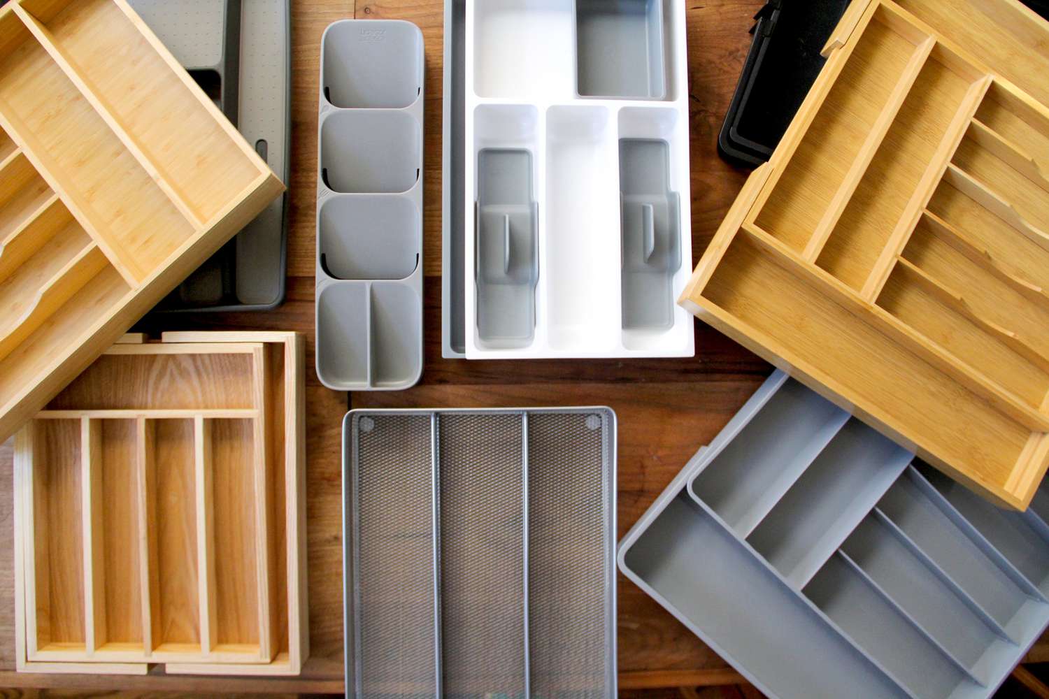 Numerous kitchen drawer organizers on a wooden countertop.