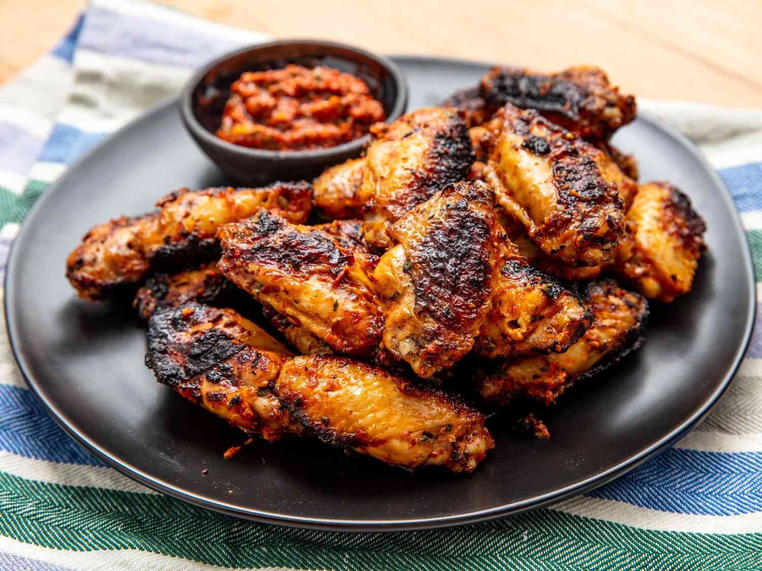 Grilled Turkish chicken wings on a plate with a dipping sauce. 