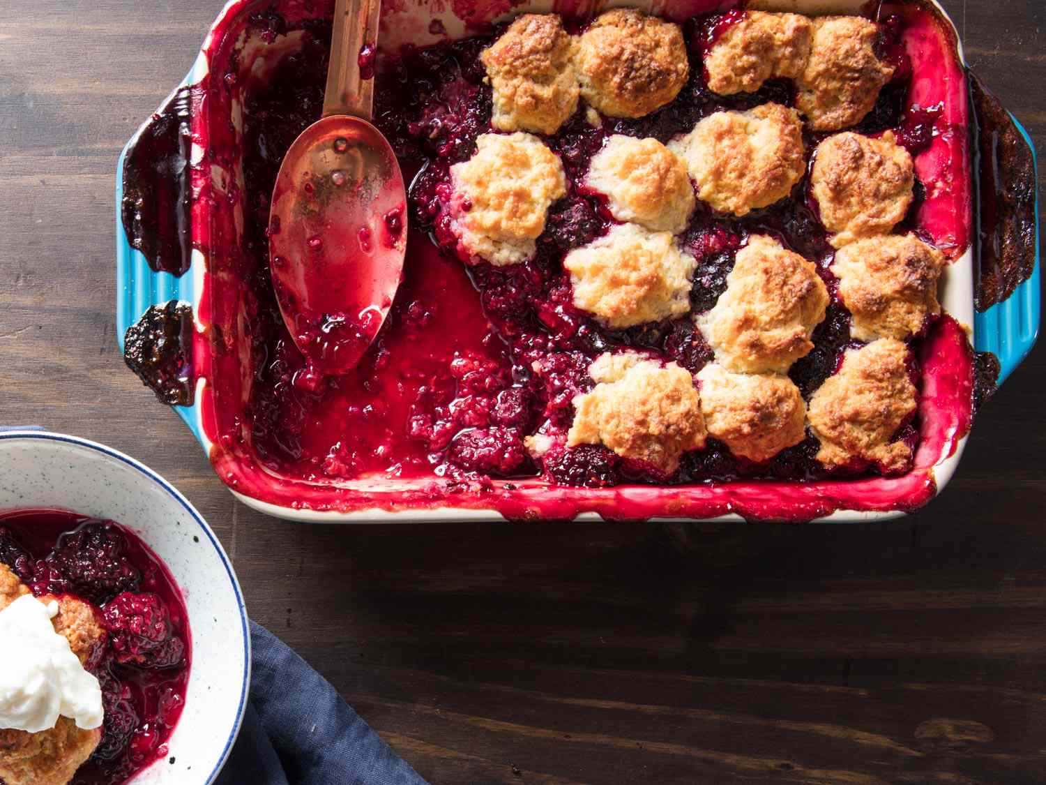 Overhead shot of the finished cobbler being served at a table, straight out of the baking dish.