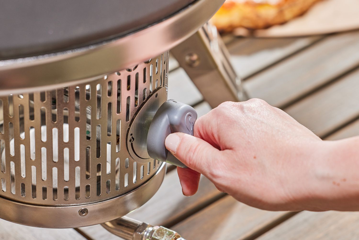 A hand turning a nob on the Gozney Roccbox Pizza Oven
