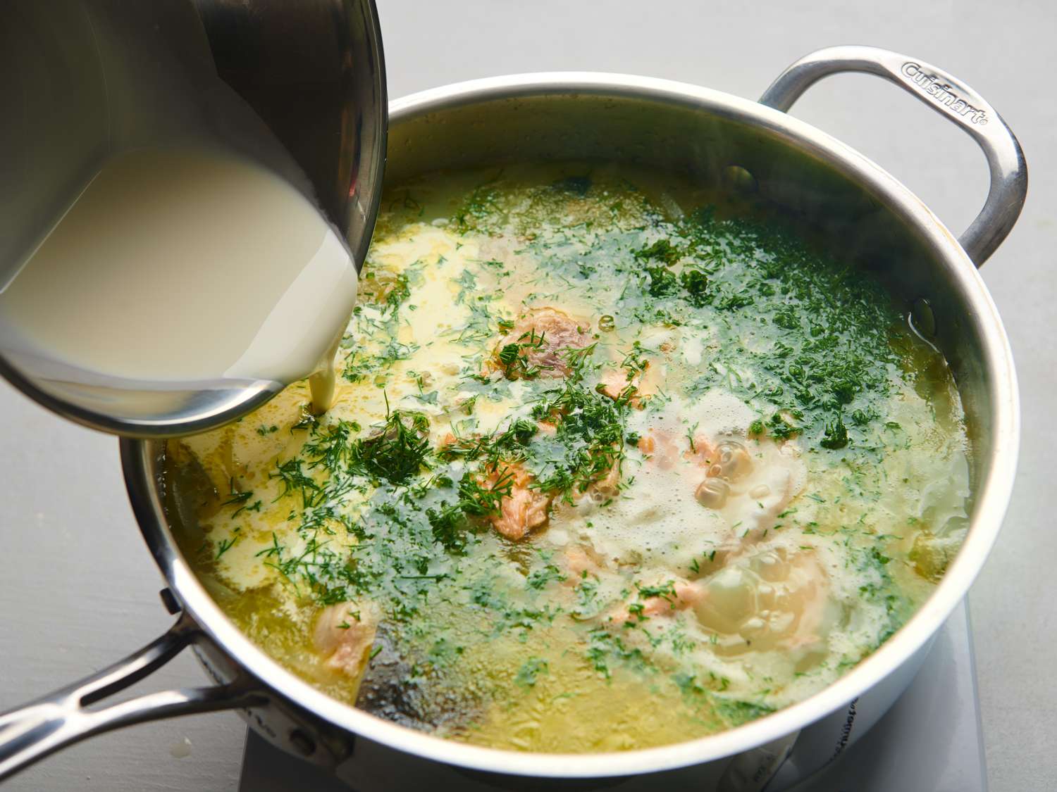 Fresh cream being poured into the sautÃ© pan, which holds the soup.