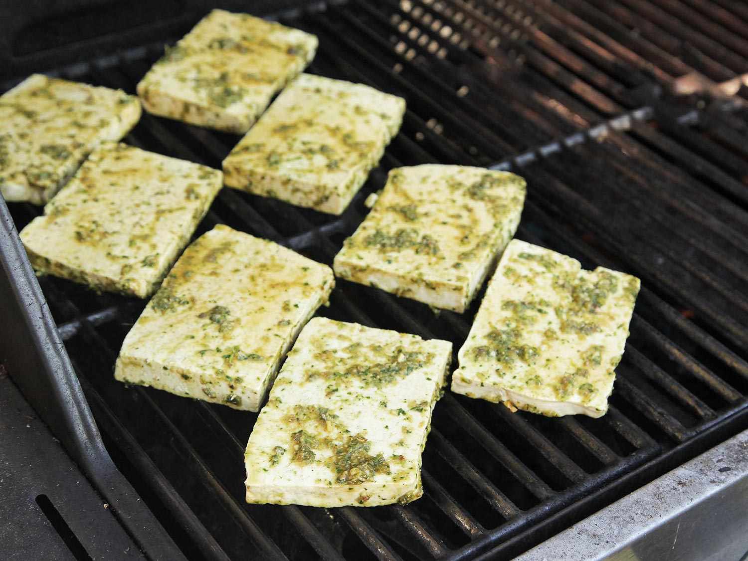 Marinated slices of tofu on a grill.