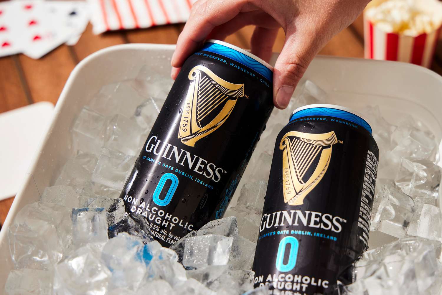 a hand pulling a guinness zero out of a bucket of ice