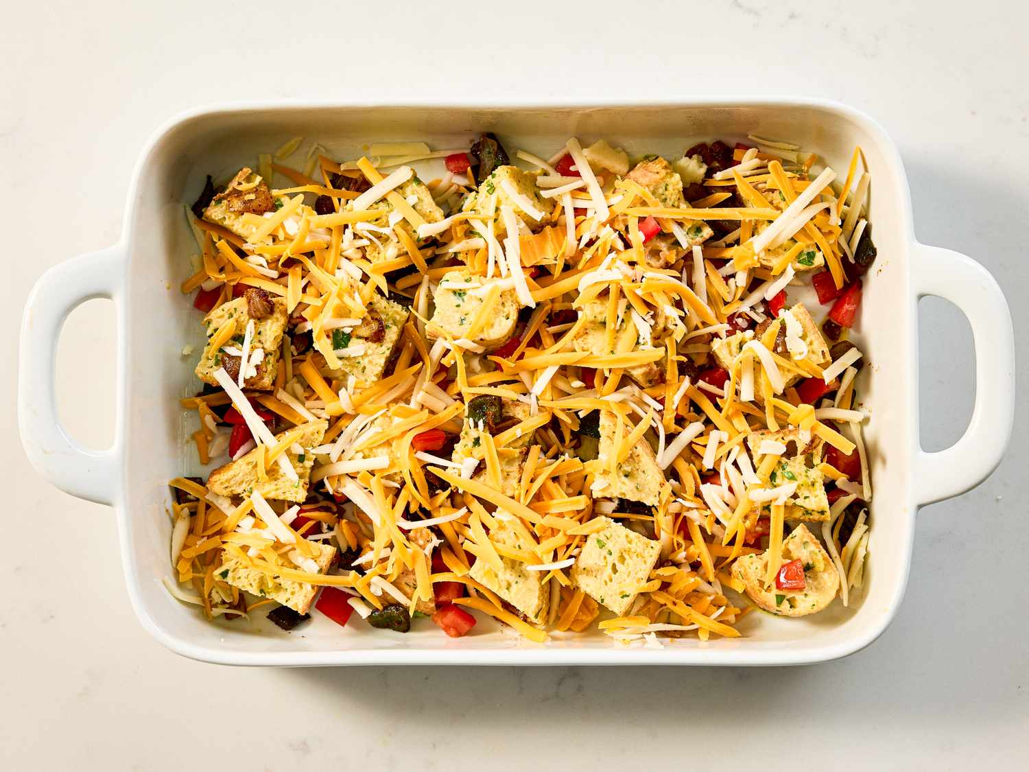 A breakfast strata with eggs cheese and vegetables prepared in a white baking dish