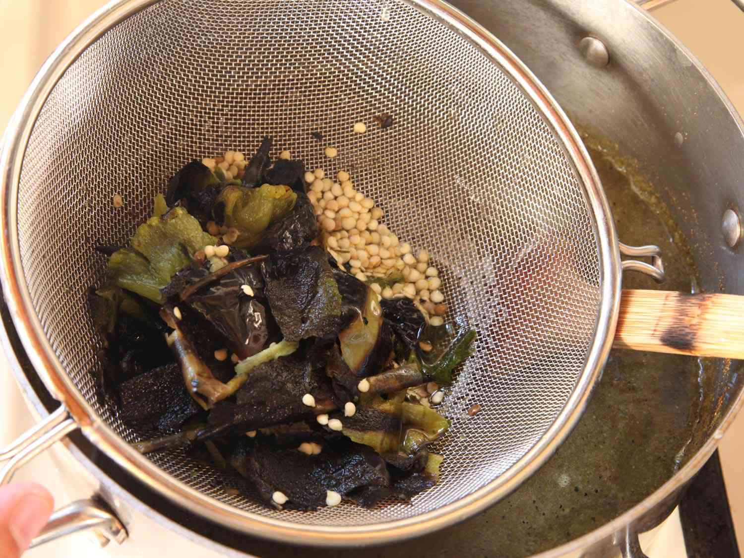 Straining chicken stock out of chile skins into pot.