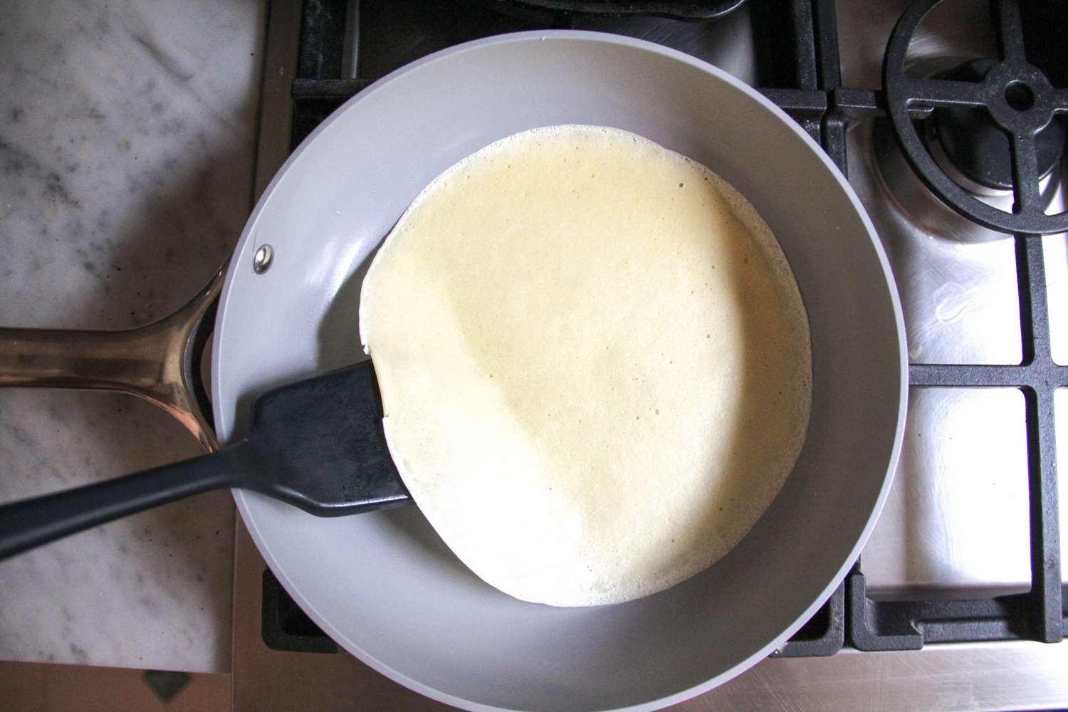 A spatula scooping food in the Caraway Nonstick Ceramic Frying Pan